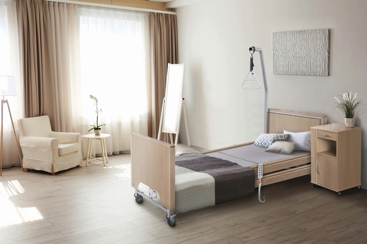 Ein eingerichtetes Zimmer mit Pflegebett, Kommode und mehr Möbel.