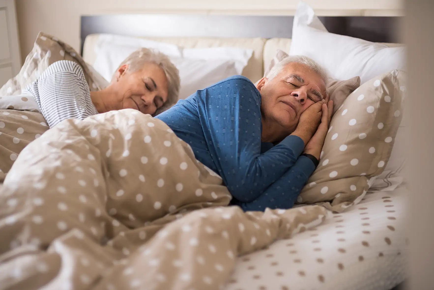 Ein Senioren-Paar schläft in einem komfortablen Bett.