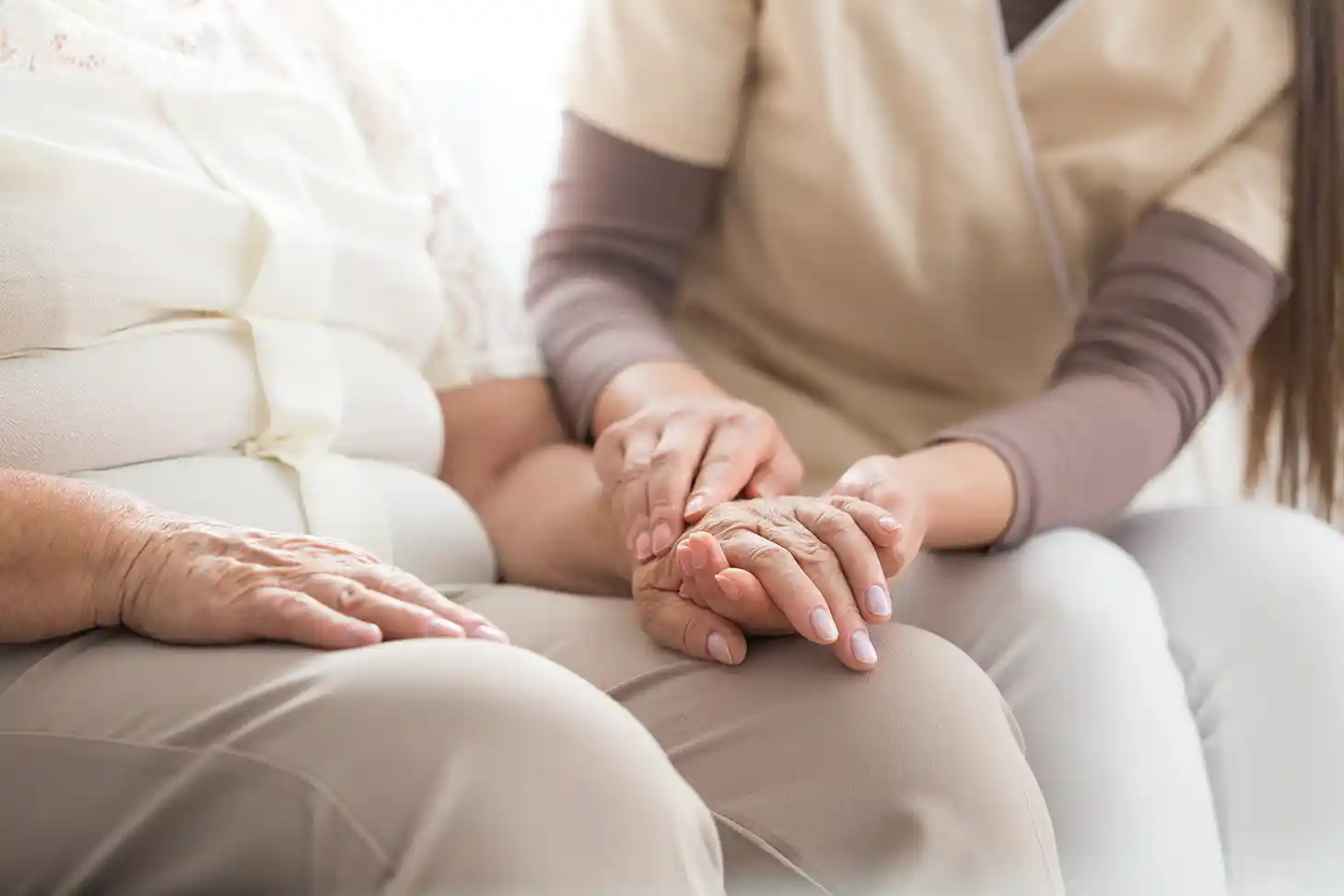 Junge Frau hält die Hand einer Älteren Frau.