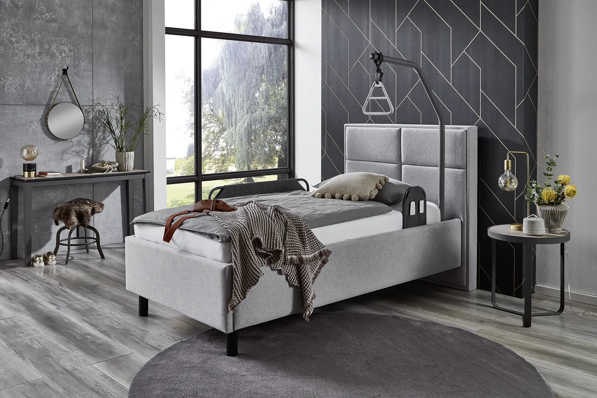 Elbacare Pflegebett mit beigen Stoffhussen und zweigeteiltem Aluminium-Seitengitter in einem modern eingerichteten Schlafzimmer – wohnliches, elektrisch verstellbares Pflegebett.